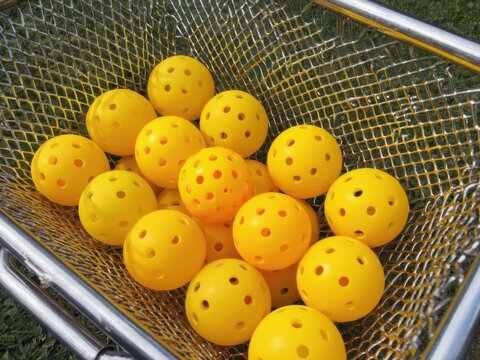 Pickleballs stacked in metal basket