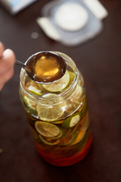 Glass jar filled with fresh lime slices preserved in honey, creating a homemade honey lime infusion. Natural ingredients for refreshing drinks, wellness, and traditional food preservation