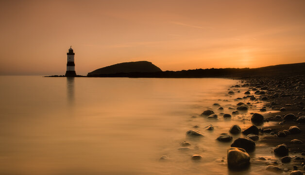 Penmon Point and Trwyn Du Lighthouse on Anglesey, with the distinctive black and white lighthouse surrounded by sea on the North Wales coast.
