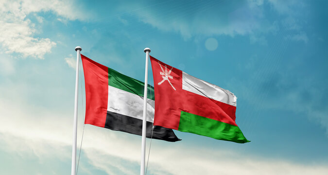 United Arab Emirates Oman friendship flags are waving in the sky. Two country flag for agreement or deal. UAE Oman national flag for commitment.