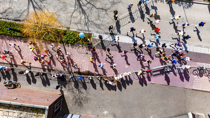 Obraz premium Aerial drone view of people running half marathon race in city, shadows of runners on road racing sport competition, top-down view of athletes and spectators, Venlo, the Netherlands