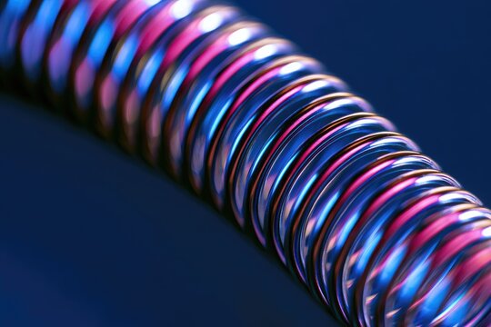 Metallic coil glows with vibrant pink, blue, and purple light against dark background