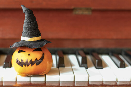 Halloween decoration with a cute orange pumpkin face on piano keys. 