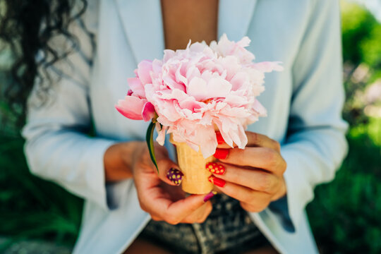 Woman holding a peony flower in an ice cream cone