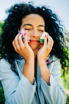 Young woman gently holds flowers to her cheeks