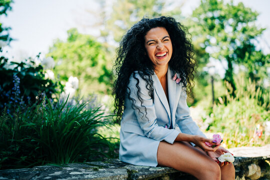 Happy woman with curly hair laughing in a sunny garden