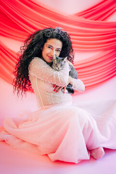 Woman in a fancy dress lovingly holding a cat