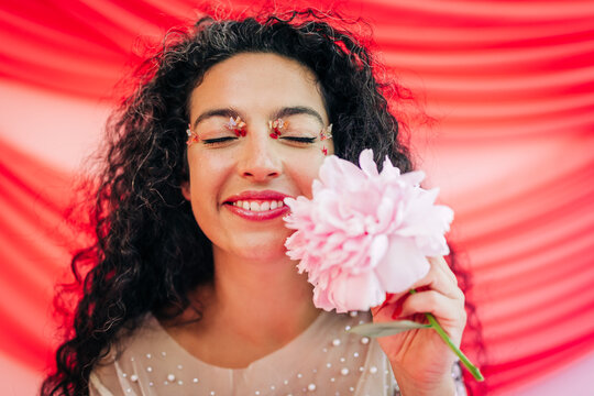 Happy woman with flower eye makeup holding a peony