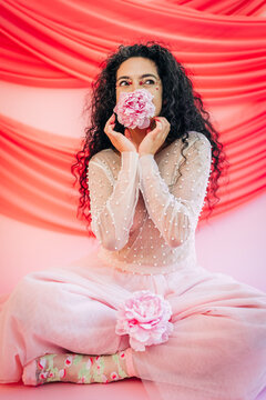 Woman with curly hair holding pink peony flower