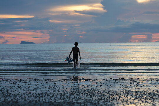 Child walking into the sea at sunset on Koh Phangan, Thailand