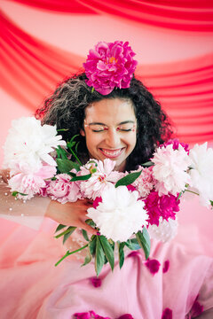 Joyful woman with eyes closed holding peony flowers