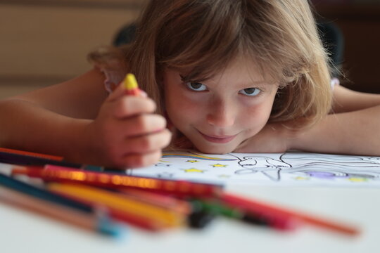 Young girl coloring a unicorn picture with playful expression