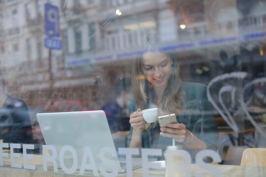 Happy woman checks phone in a city coffee shop