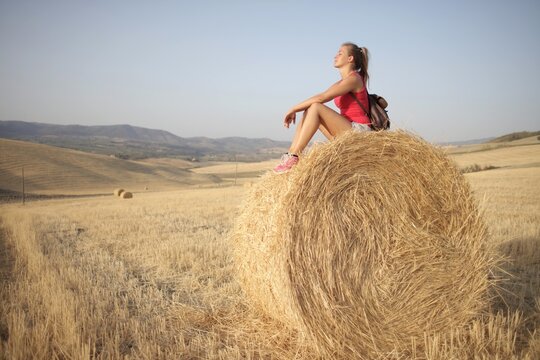 Young woman relaxing on a hay bale in summer