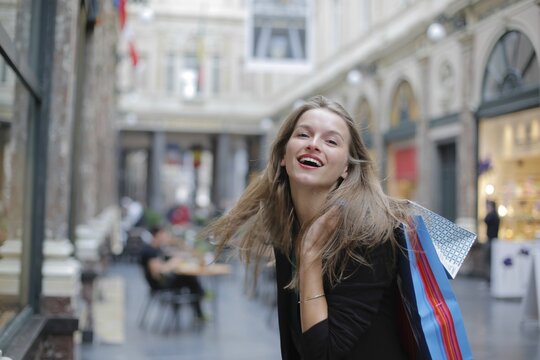 Joyful young woman laughing with shopping bags