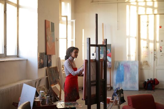 Young female artist painting in sunlit studio