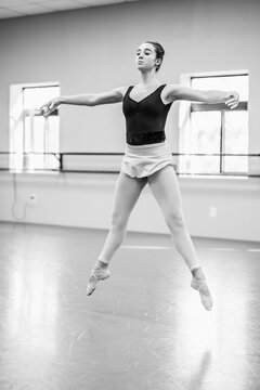 Ballerina performing a graceful jump during rehearsal in studio