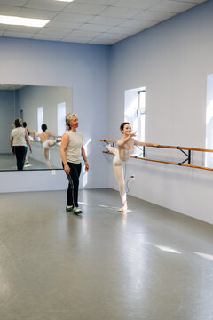 Ballet dancer practicing at barre with instructor