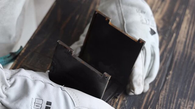 Close up of metalworker throwing square metal blanks on iron table in workshop