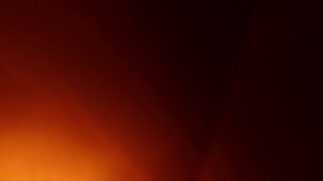 Abstract dark background with warm glowing orange light flare.
