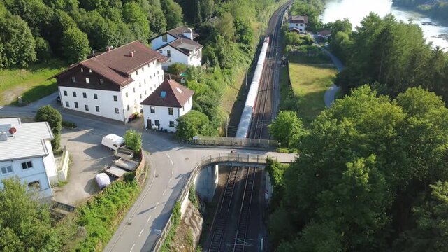 Aerial view of a passenger train passing under a bridge by the Inn river