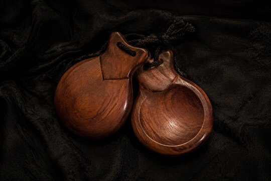 Traditional flamenco castanets resting on dark textured fabric.