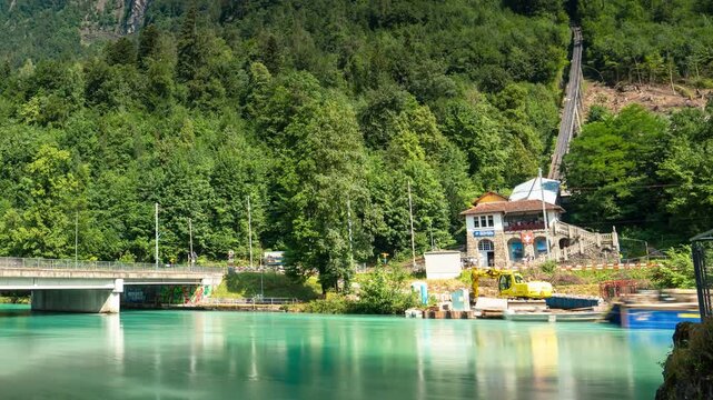 Interlaken Switzerland scenic timelapse of the iconic Harderbahn funicular railway track ascending mountain forest by turquoise Aare river bridge