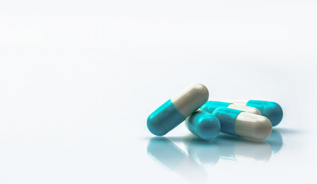 Blue and white capsules pill isolated on white background with shadow and copy space. Global healthcare concept. Antibiotics drug resistance. Antimicrobial capsule pills. Pharmaceutical industry.