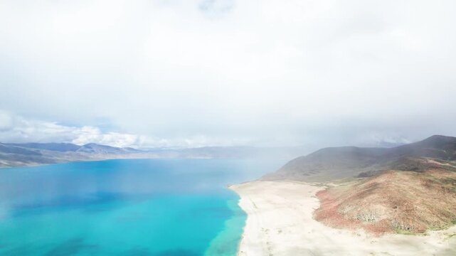 Drone view of Pegu Tso lake or Peikucuo in sunny day in Shigatse, Tibet, China, beautiful peaceful turquoise sea with mountains reflections in Xizang, 4k real time footage travel concept