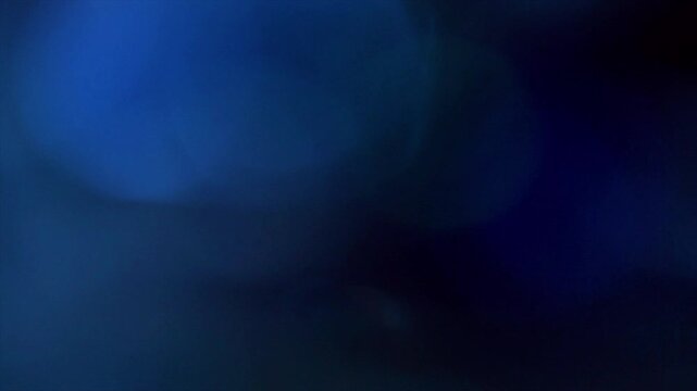 Abstract dark blue light bokeh background with subtle glowing red accent.