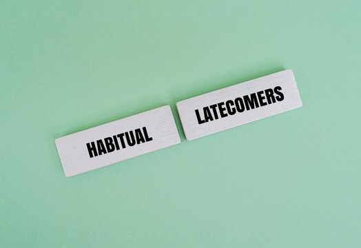 Wooden blocks with the text "HABITUAL LATECOMERS" on a green background. Concept for poor time management, unreliability, and chronic lateness at work, school, or meetings