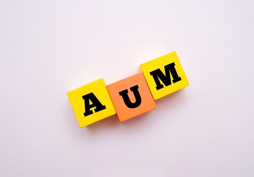 Colorful blocks with text AUM. AUM acronym for "ASSETS UNDER MANAGEMENT". Concept for financial metrics, corporate asset tracking, and capital growth