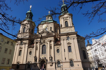 Fototapeta premium Prague, Czech Republic, March 27th&nbsp;2026: The monumental green dome and soaring bell tower of the Baroque Church of Saint Nicholas dominate the historic skyline of Prague's Lesser Town.