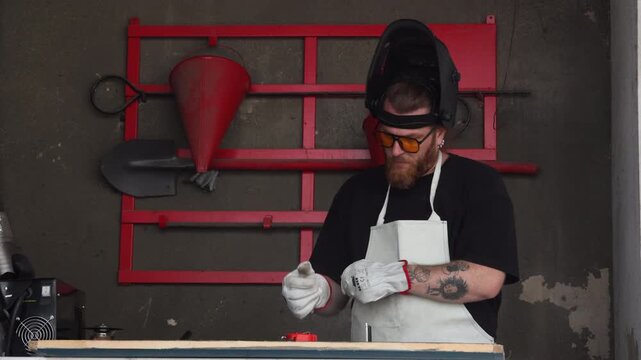 Close up of a craftsman hands putting on white protective leather gloves in a workshop