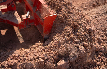 Construction tractor with specialized dozer blade pushing and grading soil at excavation site. Heavy machinery transforming raw land into prepared foundation for upcoming building development project. © Fahroni