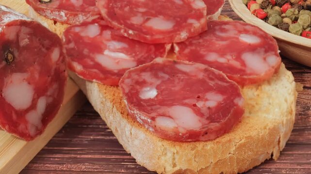 Homemade salami with pepper on a slice of bread with animal fat