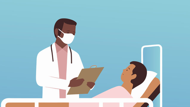 Doctor examines patient in hospital room with clipboard and protective mask