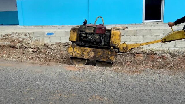 Industrial soil compactor machine operating on a construction site for road paving and ground leveling