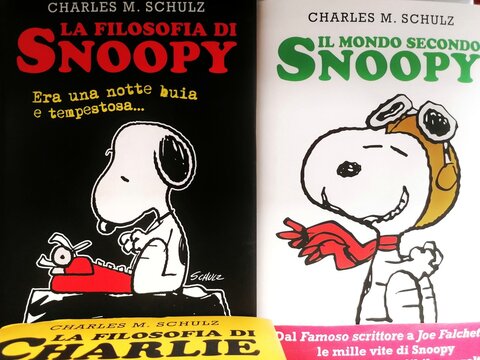 Rome, Italy - April 20, 2023, detail of the book covers of Snoopy's Philosophy. It Was a Dark and Stormy Night and The World According to Snoopy, on a bookstore shelf.