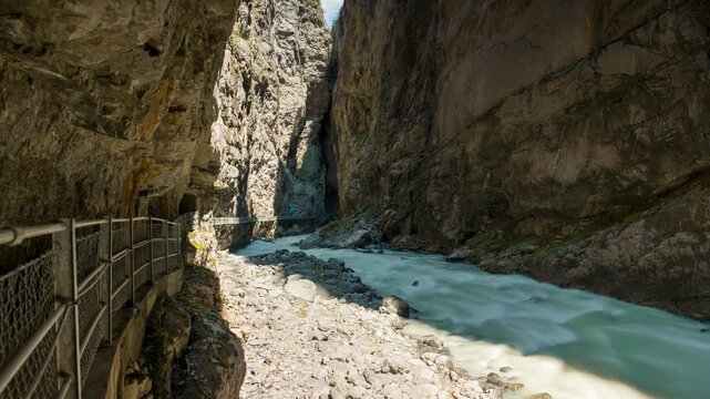 Grindelwald canyon timelapse of rushing river water through the dramatic glacier gorge with moving shadows on steep rock cliffs