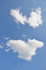 Two white clouds shaped like hearts against a clear blue sky create a playful and romantic visual effect. Nature, beautiful weather, sky and clouds,  natural environment. © Mariana