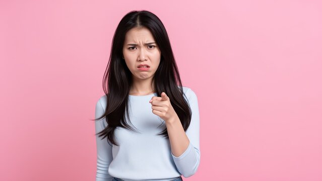 Angry Asian Woman Points Finger: A young Asian woman with long black hair and bangs, wearing a light blue top and silver skirt.