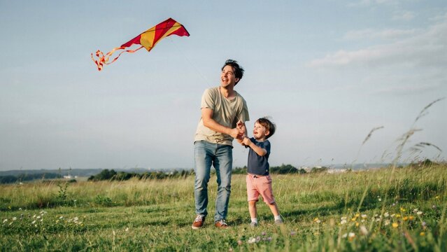 Father and son flying colorful kite in grassy field with smiling father young yellow kite sunlit Looking