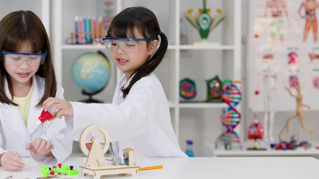 Two Young Girls in Lab Coats Conducting Science Experiment in Classroom