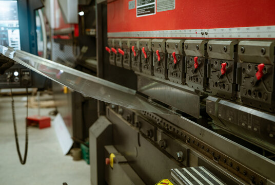 CNC press brake engages a metal panel. Precision tooling shapes each section. Manufacturing operations. Accurate setup and consistent force during sheet forming. Metal bending machine in factory.