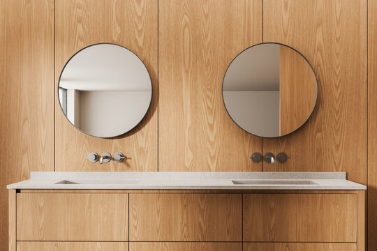 Modern wooden bathroom interior with dual round mirrors, minimalist sinks, warm wood textures, clean lines, contemporary design aesthetics showcased in detail. 3D Rendering