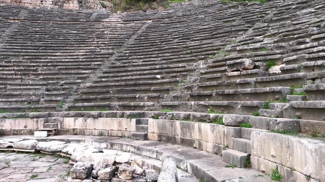 Wide shot 180 degree camera pan at the base of the ancient stone amphitheatre at the Oracle of Delphi in daytime

