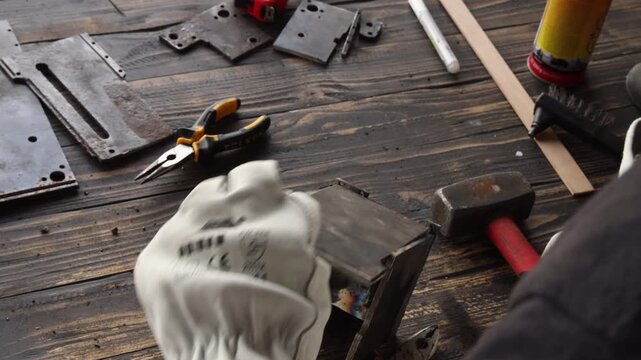 Professional blacksmith in protective uniform working with hand tools in factory