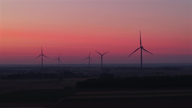 Wind farm, wind turbines, dawn, sunrise, rotating turbine blades, flashing red aviation lights, renewable energy.