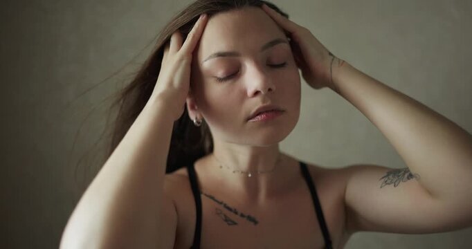 Cinematic portrait of attractive woman touching her blowed hair in dark room, slow motion